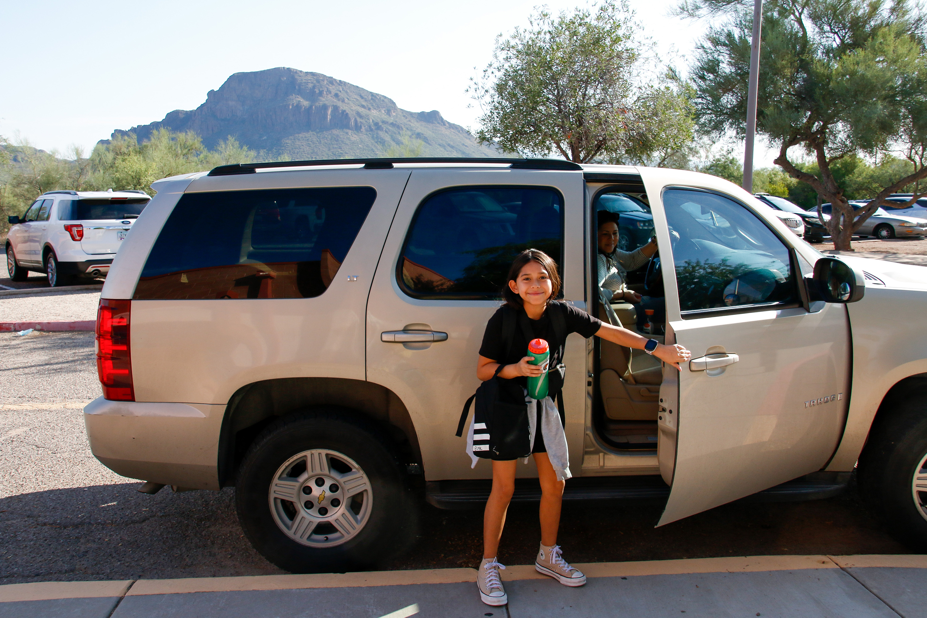 A girl smiles as she gets out of her family's car on the first day