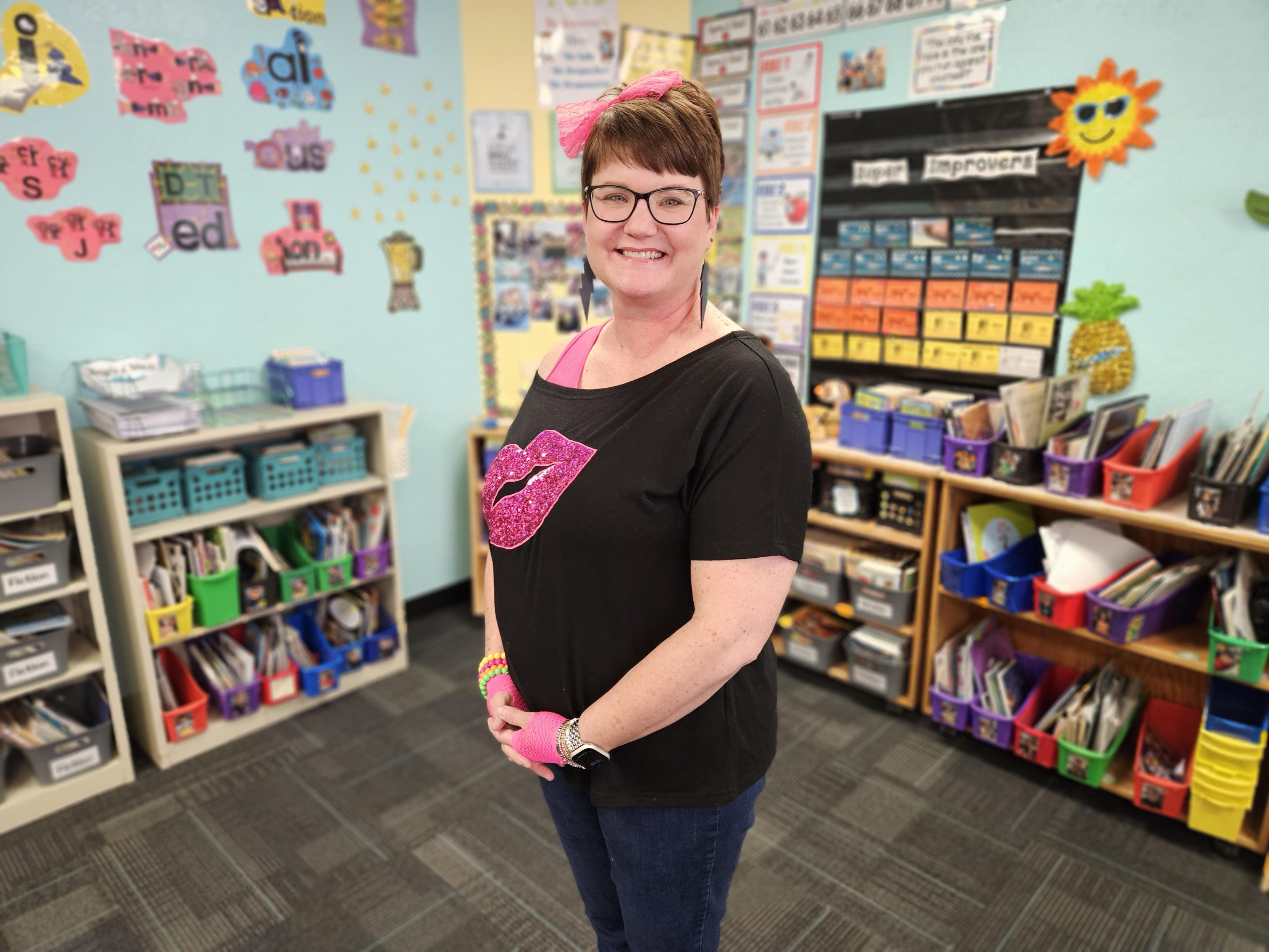 A woman in glasses smiles in her classroom