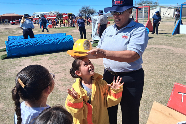 A man puts a yellow fire helmet on a little girl's head