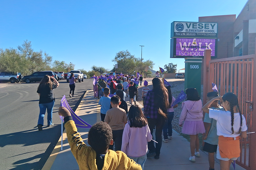 Students walk in front of the school with their purple Ruby Bridges pennants