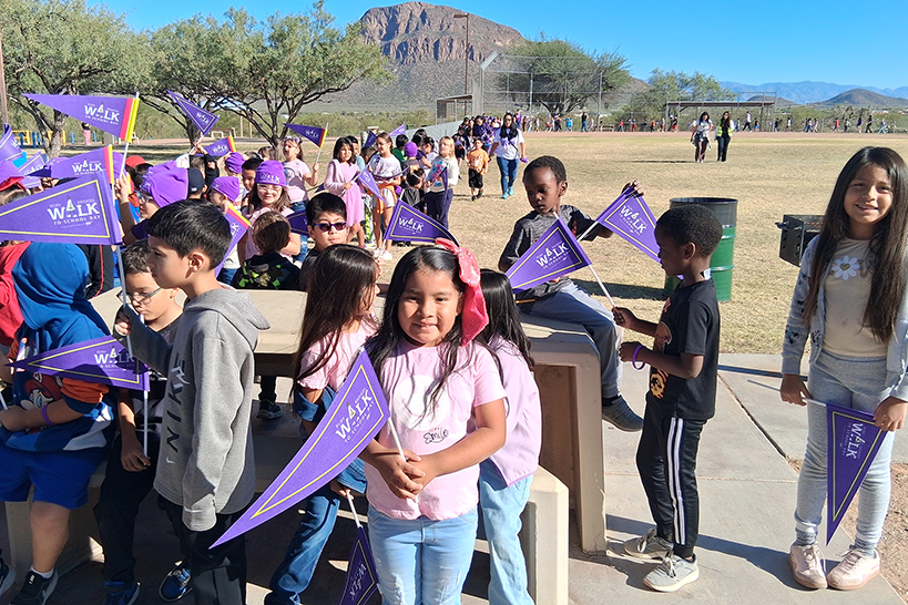 Students smile with their purple Ruby Bridges pennants as they wait to start the walk